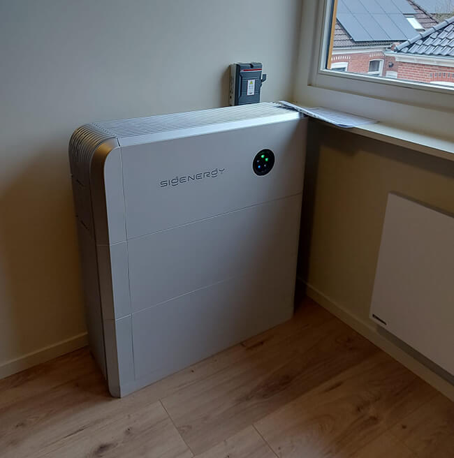 Thuisbatterij bij raam in woonkamer