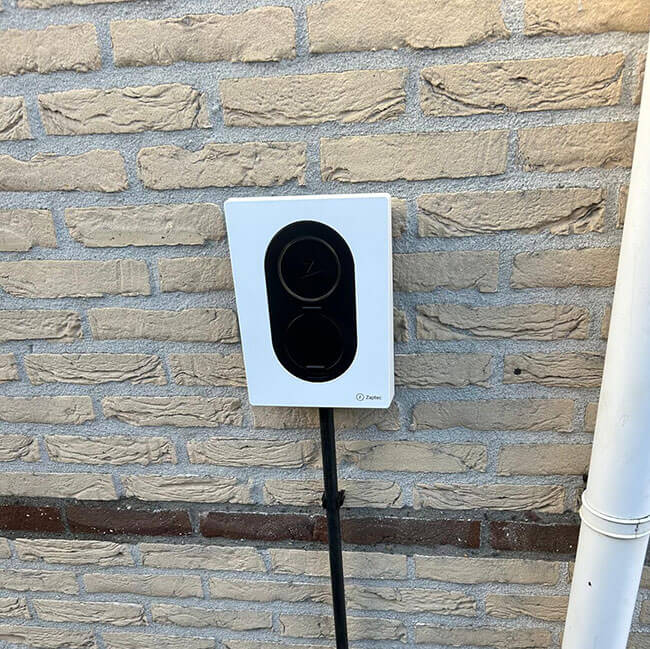 Witte laadpaal aan muur op bedrijfsterrein